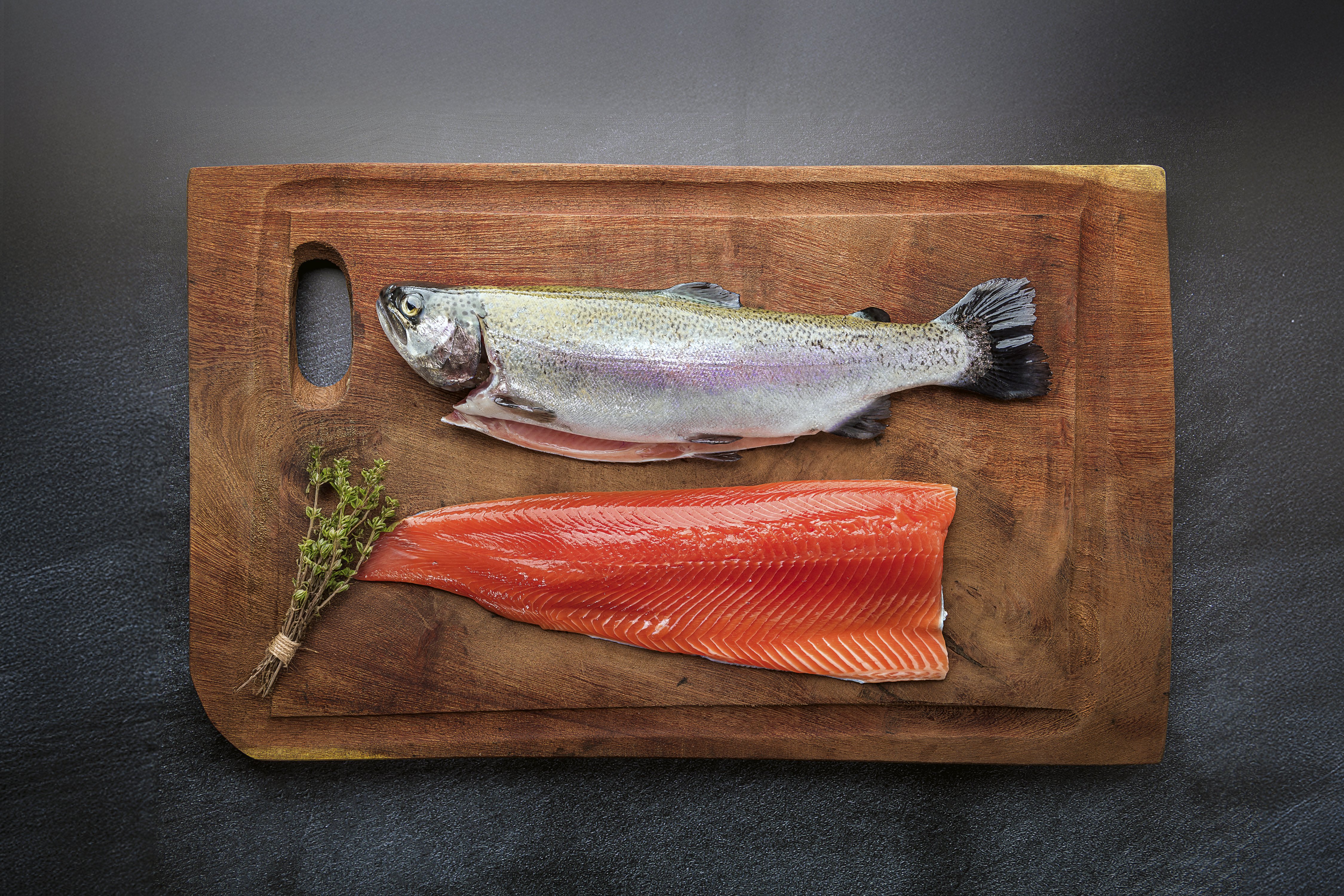 Fresh rainbow trout and fillet on wooden board